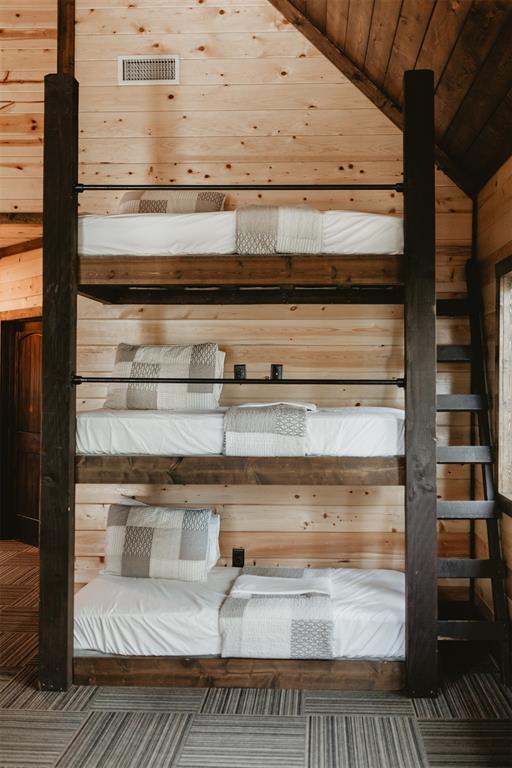 interior space with visible vents, wood walls, lofted ceiling, and wooden ceiling