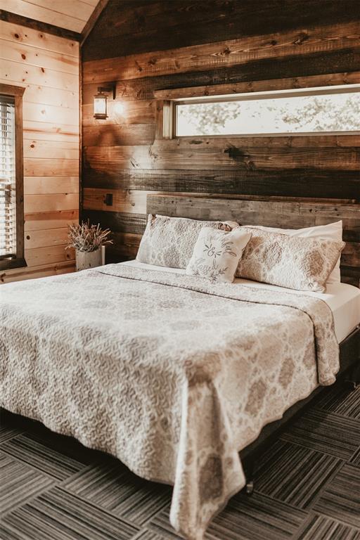 bedroom with wooden walls and lofted ceiling