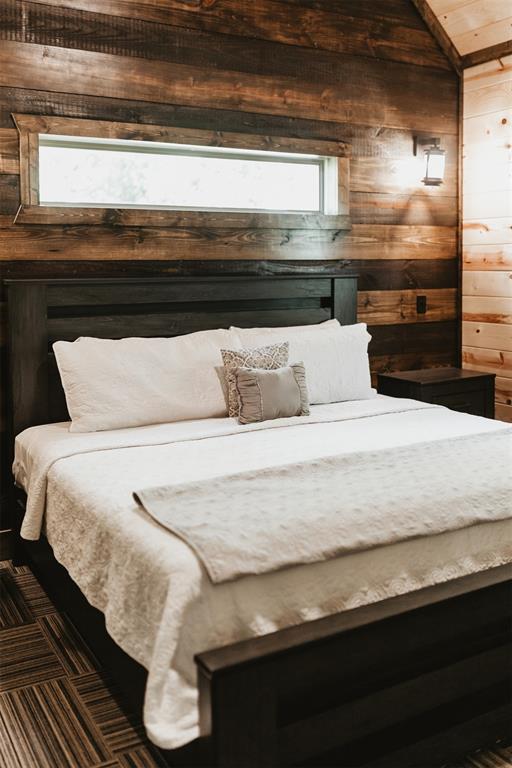 bedroom featuring wood walls and lofted ceiling