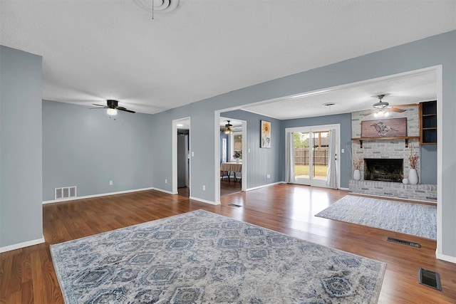 305 S Mockingbird Dr, Altus, OK 73521 - unfurnished living room with ceiling fan, a brick fireplace, wood finished floors, and visible vents