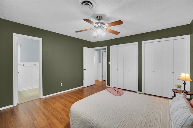 305 S Mockingbird Dr, Altus, OK 73521 - bedroom featuring ceiling fan, ensuite bathroom, two closets, and wood finished floors