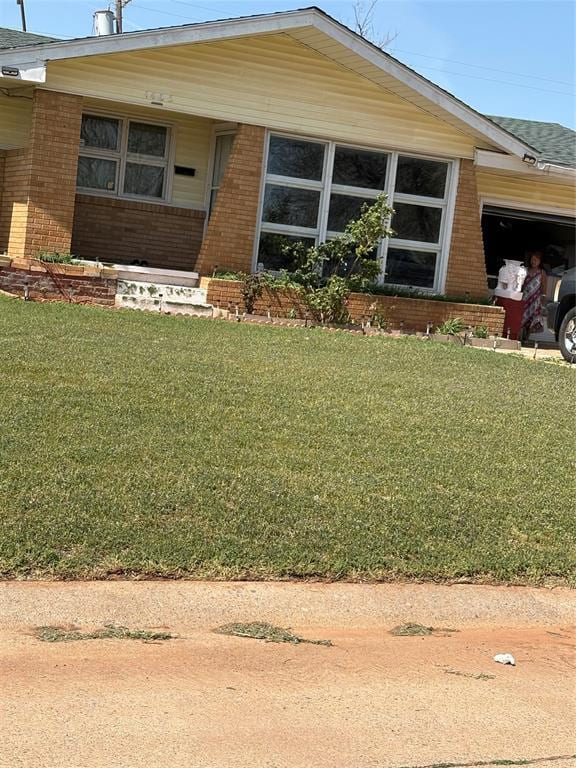 view of front facade with brick siding, a front lawn, and an attached garage