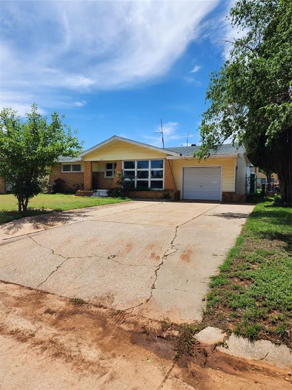 ranch-style home featuring a garage, concrete driveway, a front lawn, and brick siding