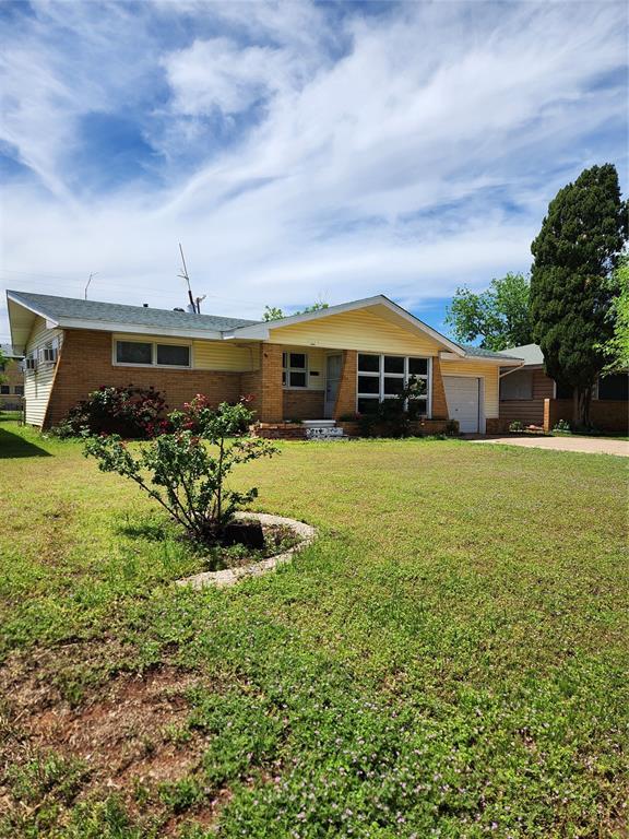 ranch-style home with an attached garage, a front yard, driveway, and brick siding