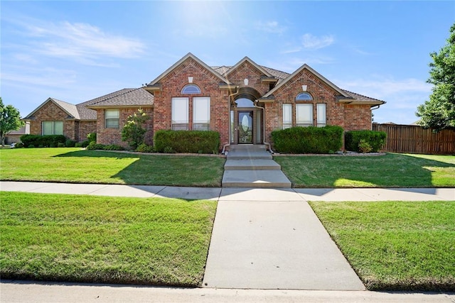traditional-style house with brick siding, fence, and a front yard