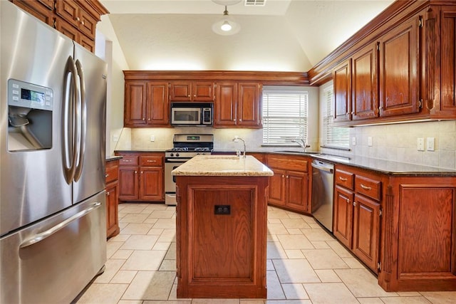 kitchen featuring lofted ceiling, a sink, decorative backsplash, stainless steel appliances, and an island with sink