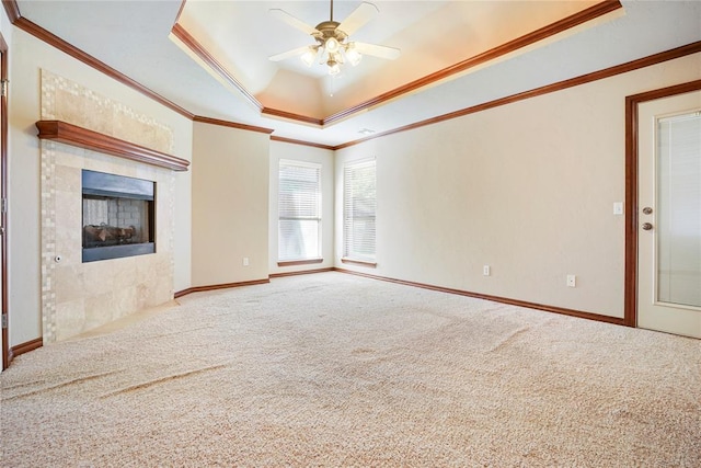 unfurnished living room featuring crown molding, carpet floors, a ceiling fan, a tray ceiling, and baseboards