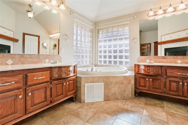 bathroom featuring a fireplace, visible vents, a bath, and tasteful backsplash
