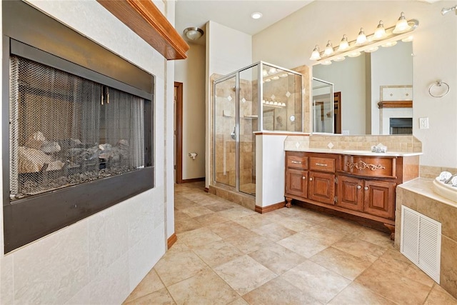 bathroom featuring a stall shower, vanity, a fireplace, and visible vents