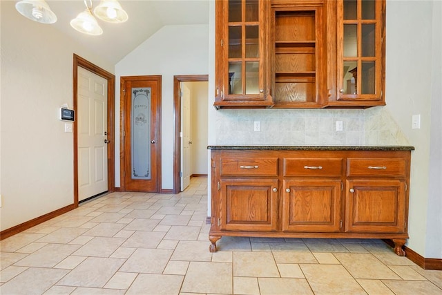 kitchen with vaulted ceiling, glass insert cabinets, baseboards, and brown cabinets