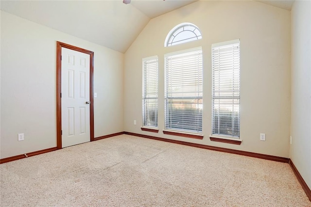 unfurnished room with lofted ceiling, carpet floors, baseboards, and a ceiling fan