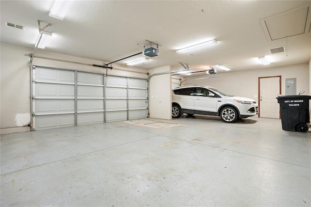 garage with visible vents, electric panel, and a garage door opener