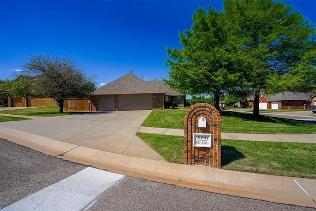 single story home with driveway, brick siding, fence, a garage, and a front lawn