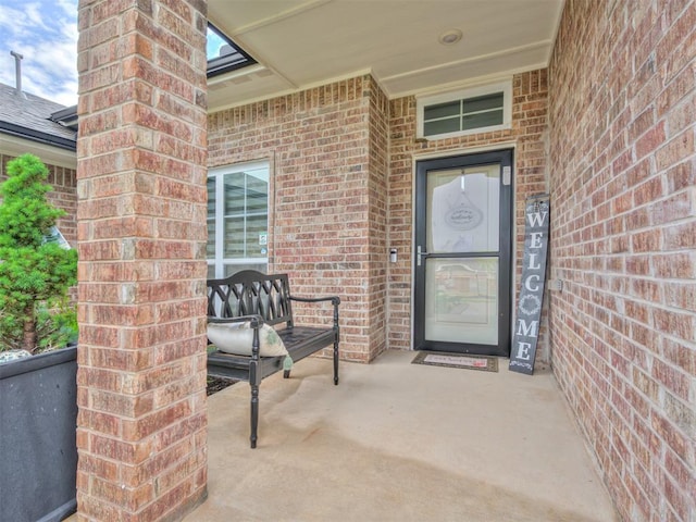 view of exterior entry with a porch and brick siding
