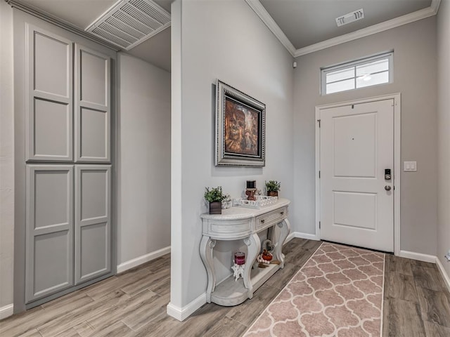 entryway featuring baseboards, visible vents, ornamental molding, and light wood-type flooring