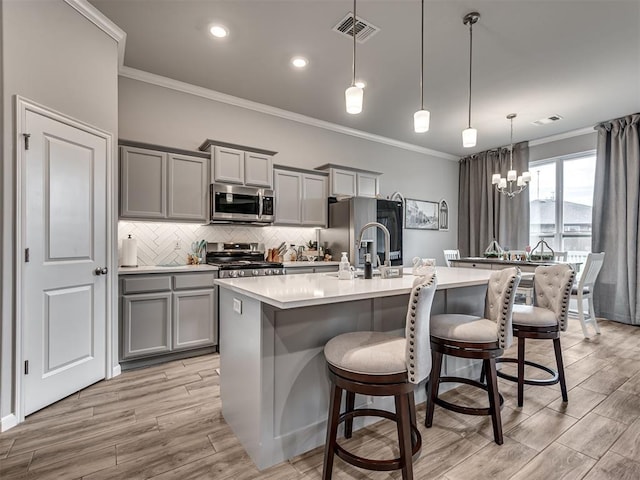 kitchen with appliances with stainless steel finishes, visible vents, ornamental molding, and gray cabinets