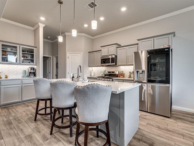 kitchen with tasteful backsplash, visible vents, stainless steel appliances, ornamental molding, and gray cabinets