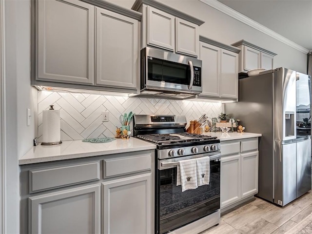 kitchen with gray cabinets, ornamental molding, and appliances with stainless steel finishes