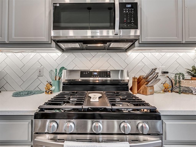 kitchen with gray cabinetry, appliances with stainless steel finishes, light countertops, and decorative backsplash