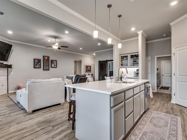 kitchen featuring open floor plan, light countertops, gray cabinets, and a sink