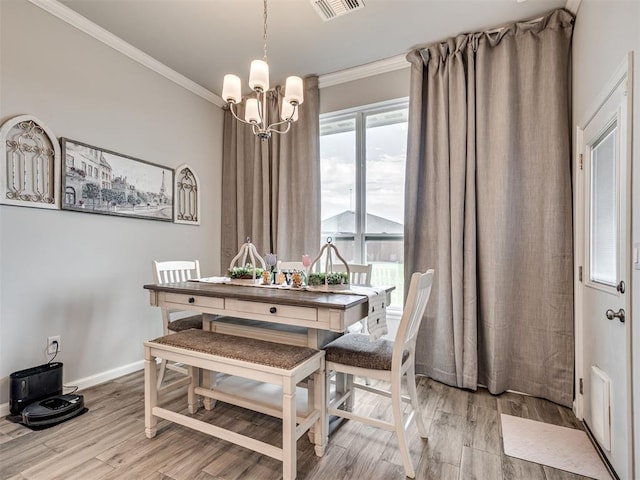 dining space with baseboards, light wood-type flooring, ornamental molding, and a notable chandelier