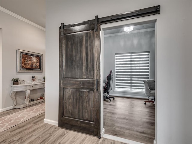 office area featuring baseboards, a barn door, ornamental molding, and wood finished floors