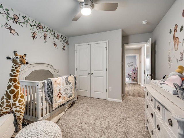 bedroom with a closet, a ceiling fan, light carpet, and baseboards