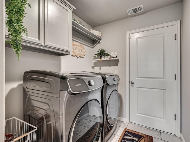 clothes washing area with baseboards, visible vents, cabinet space, and washing machine and clothes dryer