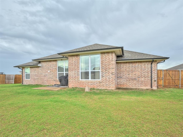 back of property with brick siding, a fenced backyard, and a yard
