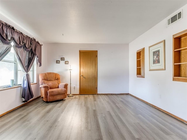 living area featuring light wood finished floors, visible vents, and baseboards