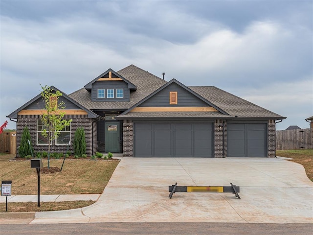craftsman house featuring concrete driveway, roof with shingles, an attached garage, fence, and brick siding
