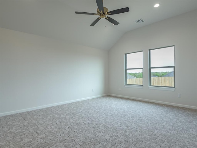 spare room with a ceiling fan, visible vents, vaulted ceiling, carpet, and baseboards