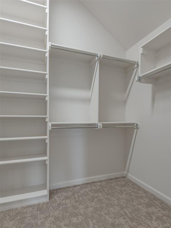 walk in closet with vaulted ceiling and carpet floors