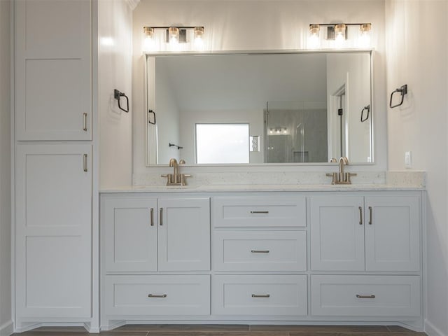 bathroom with double vanity, a stall shower, and a sink