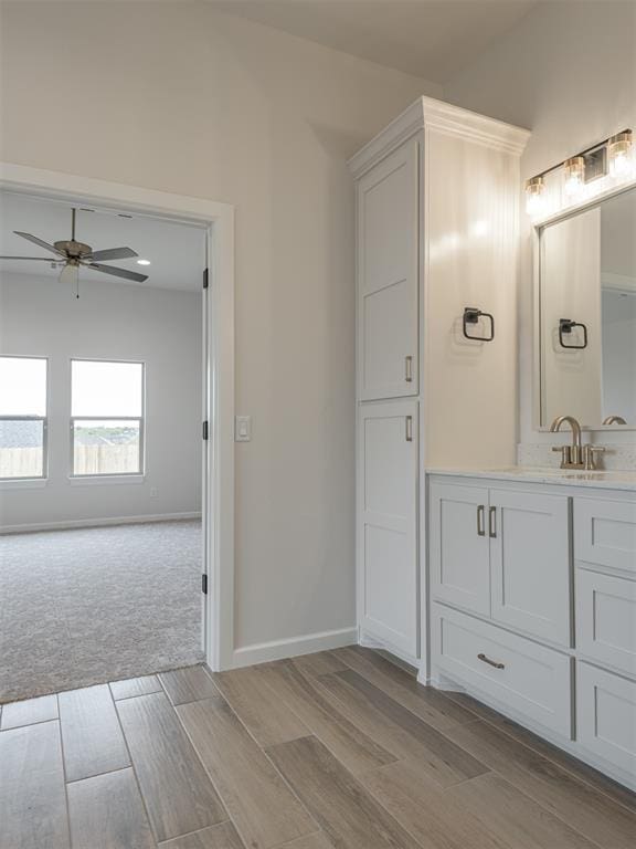 bathroom with baseboards, wood finished floors, a ceiling fan, and vanity