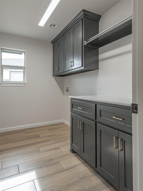 laundry room featuring hookup for a washing machine, cabinet space, light wood finished floors, baseboards, and visible vents