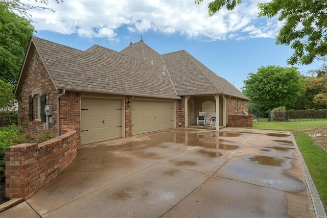 view of front facade featuring a garage, fence, brick siding, a shingled roof, and concrete driveway