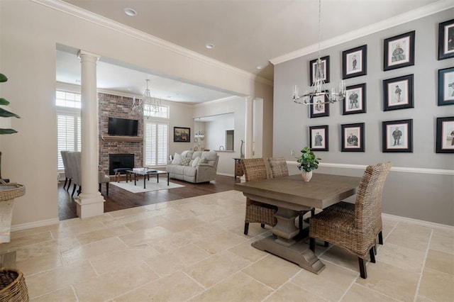 dining space featuring a brick fireplace, ornate columns, baseboards, and a chandelier