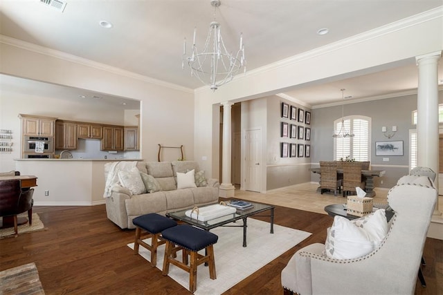 living room featuring crown molding, ornate columns, an inviting chandelier, and wood finished floors