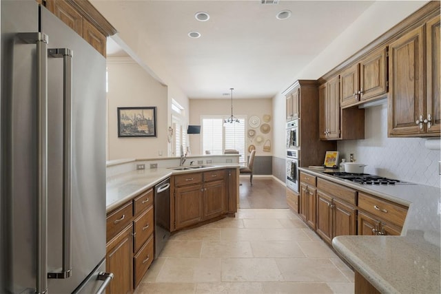 kitchen featuring pendant lighting, brown cabinets, tasteful backsplash, a sink, and appliances with stainless steel finishes