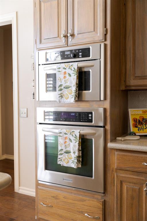 kitchen with light countertops, oven, baseboards, and wood finished floors