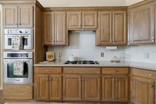 kitchen featuring light countertops, brown cabinetry, gas cooktop, and decorative backsplash