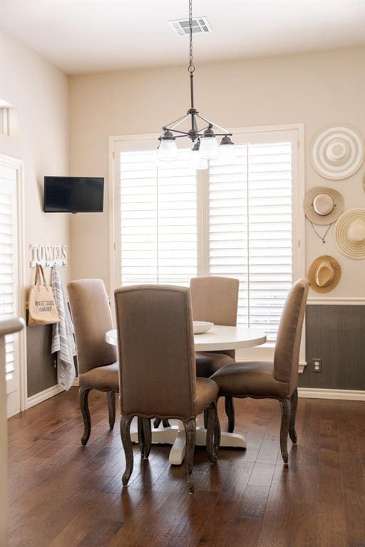 dining area featuring baseboards, visible vents, dark wood-type flooring, and a notable chandelier