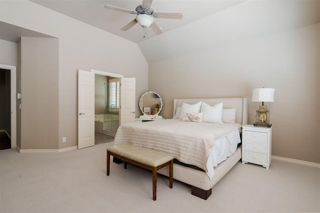 bedroom featuring ceiling fan, light colored carpet, ensuite bath, baseboards, and vaulted ceiling