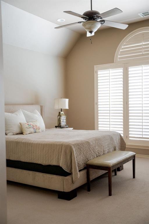 carpeted bedroom featuring multiple windows, vaulted ceiling, and visible vents