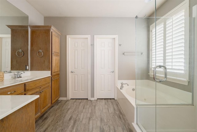 full bathroom with a garden tub, wood finished floors, a healthy amount of sunlight, and vanity