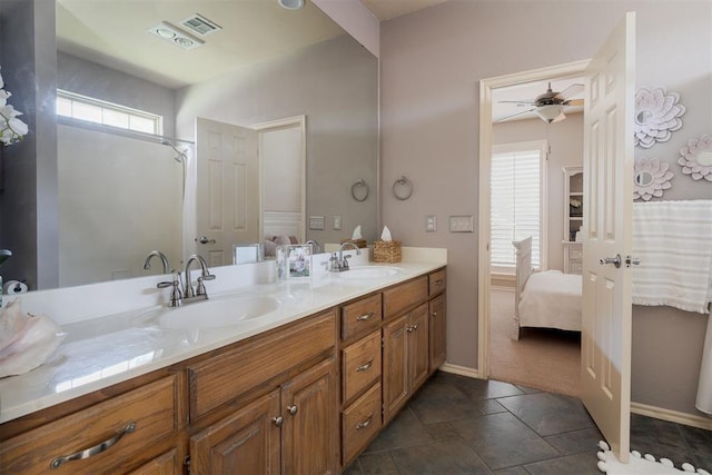 ensuite bathroom with a sink, baseboards, a ceiling fan, and double vanity