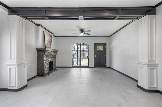 unfurnished living room featuring ornate columns, a ceiling fan, a stone fireplace, and baseboards