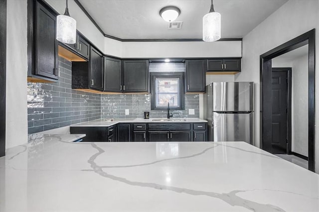 kitchen with visible vents, light stone countertops, decorative backsplash, and freestanding refrigerator