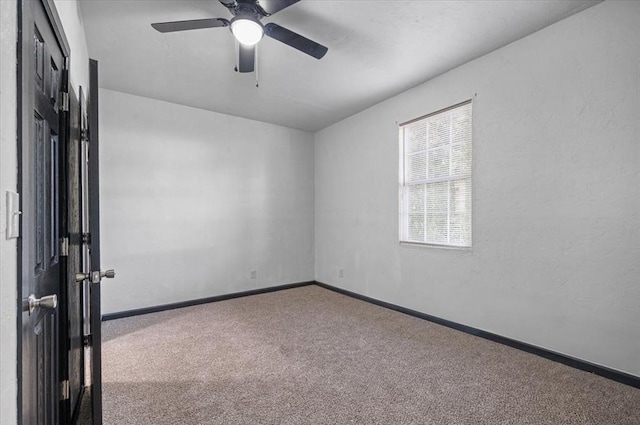 carpeted spare room with a ceiling fan and baseboards